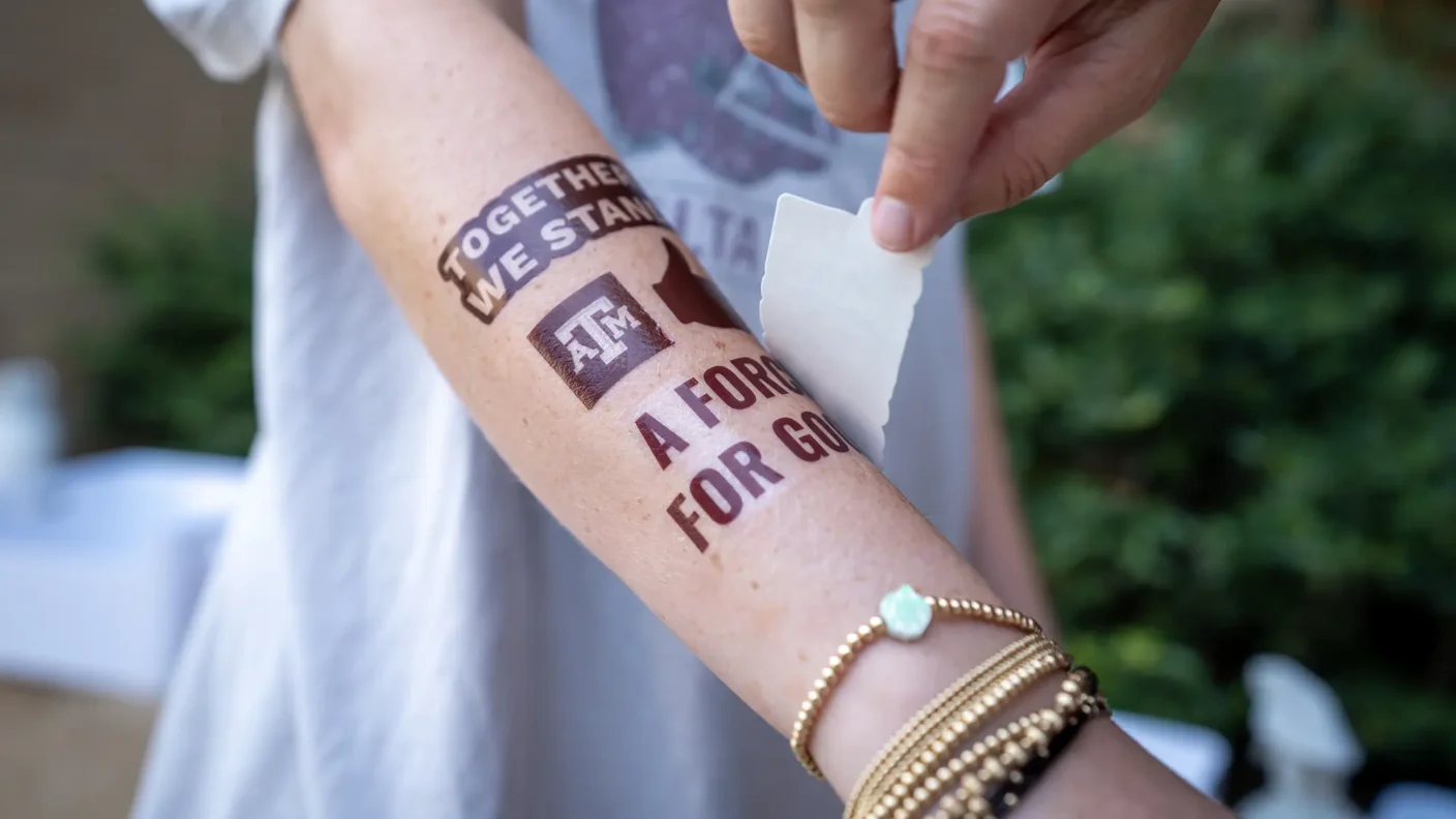 Student puts Texas A&M brand tattoos on their arm on the first day of school