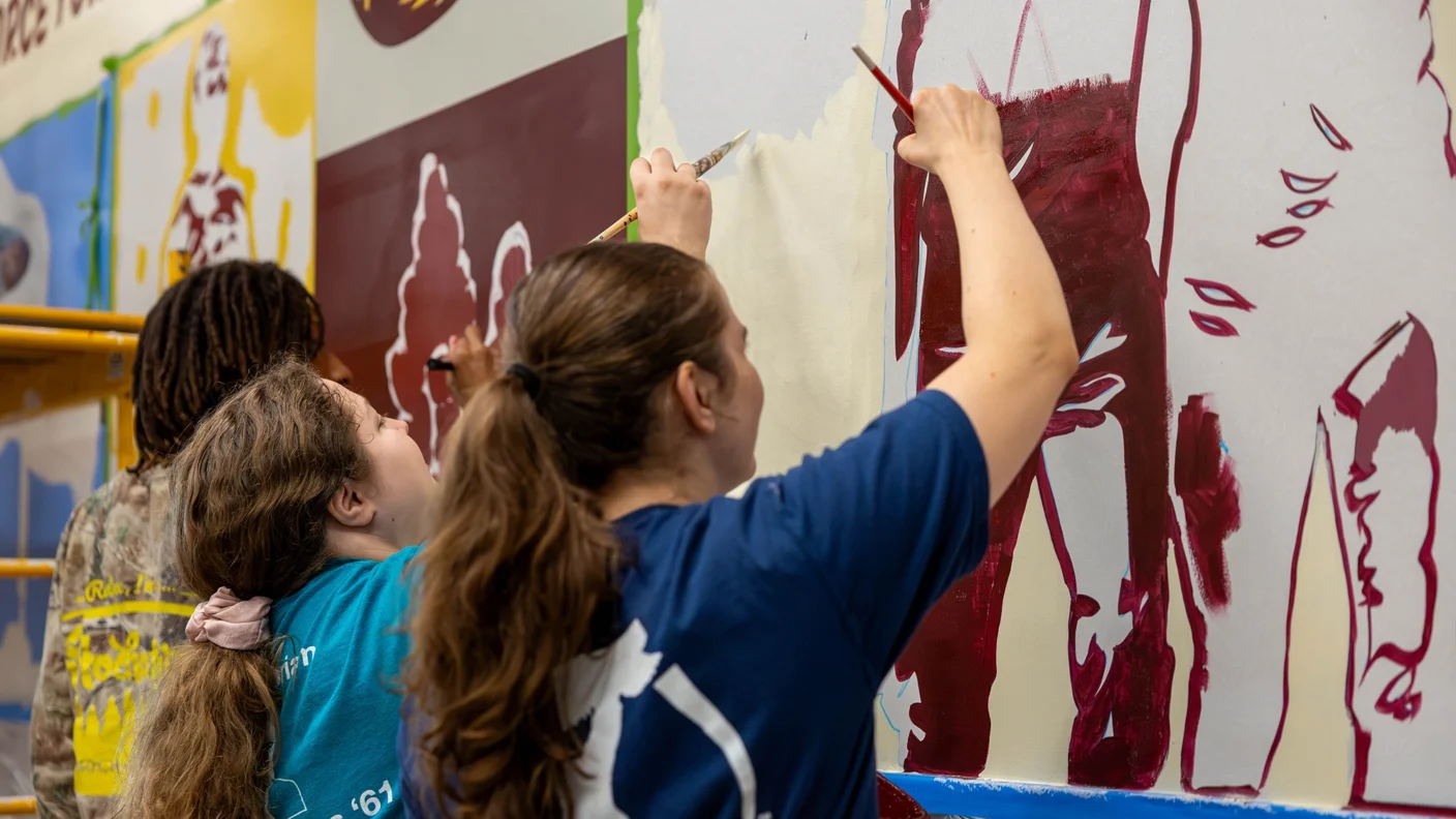 Aggie Students helping paint the Secret Walls mural in Polo Garage