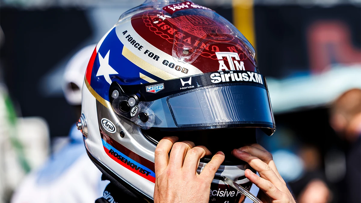 Person holding the front of the Texas A&M branded IndyCar helmet over their face